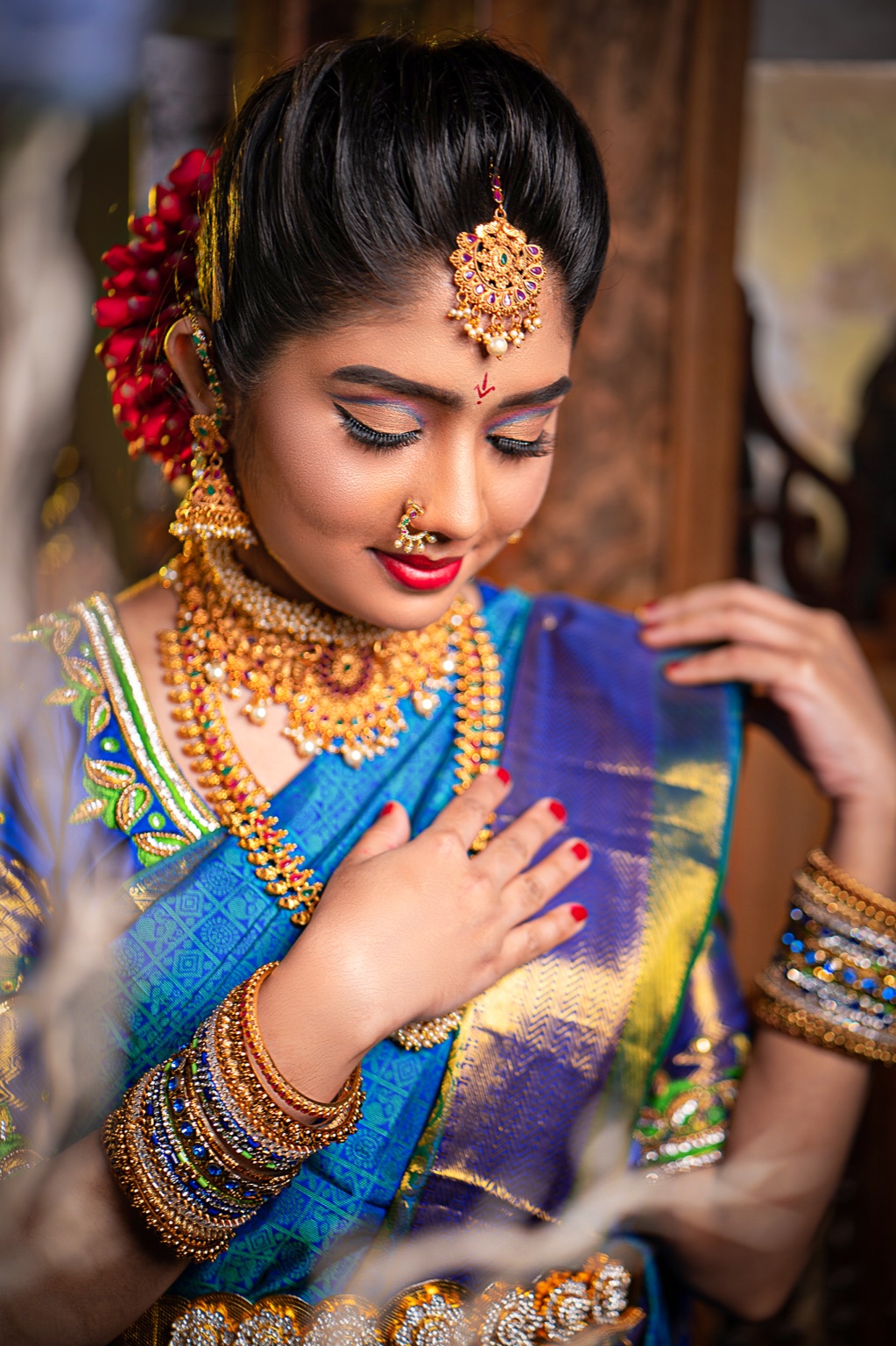 Close-up of a bride in a blue saree showing intricate jewellery and bangles