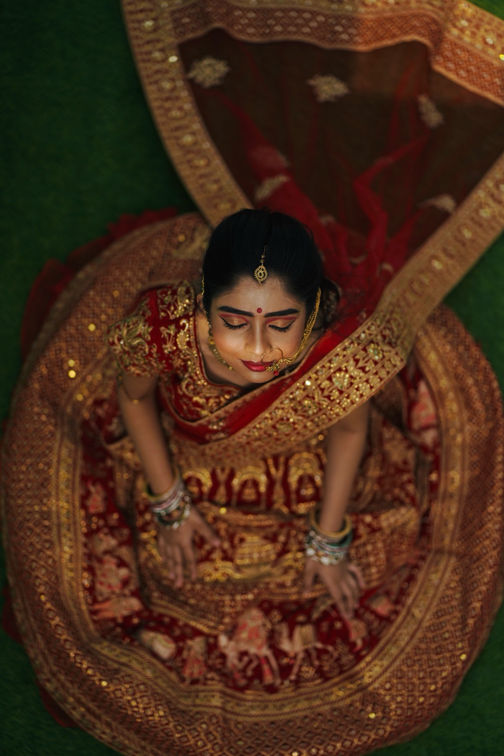 Top-down view of a bride wearing a red and gold lehenga
