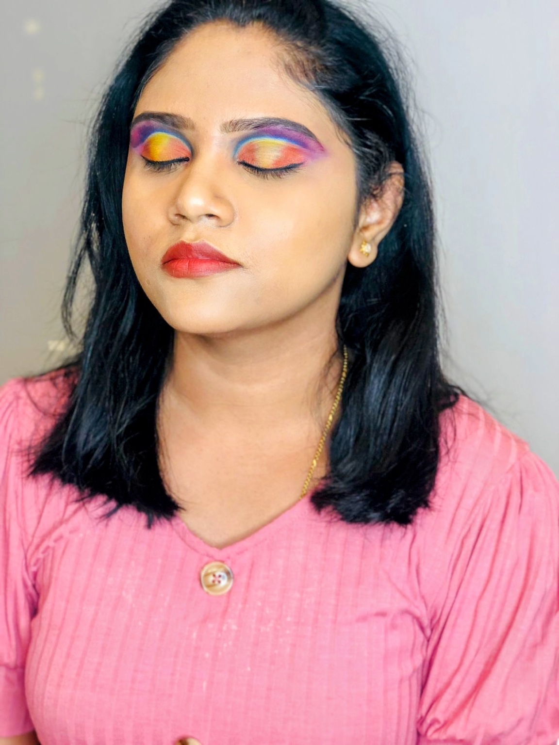 Woman with vibrant rainbow eye shadow and bold red lips